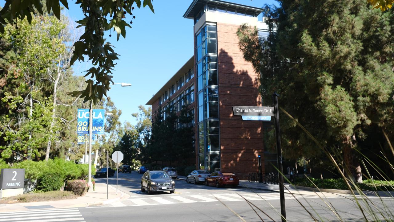 A car driving on Charles E. Young Drive passing the Engineering V Building. 